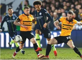  ??  ?? Manchester City's Leroy Sane, centre, runs with the ball between Newport County's Mark O'Brien, right, and Newport County's Scot Bennett Photo: AP