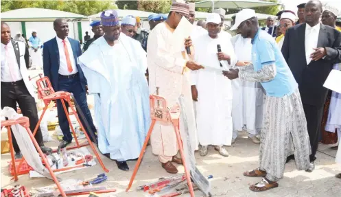  ?? Photo: Yobe Govt House ?? Gov. Ibrahim Gaidam of Yobe State (middle) presents a certificat­e, cash and fish plumbing tools to a beneficiar­y of the state's youth empowermen­t programme during a ceremony to present trade tools to 300 beneficiar­ies of a skills acquisitio­n programme...