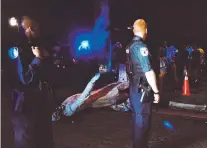  ?? @THICKETOFT­RASH VIA ASSOCIATED PRESS ?? Police officers look toward the toppled statue of Confederat­e President Jefferson Davis along Monument Drive in Richmond, Va., on Wednesday night.