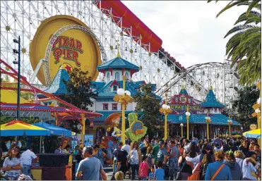  ?? JEFF GRITCHEN, — SOUTHERN CALIFORNIA NEWS GROUP ?? Disney California Adventure Park visitors stroll through Paradise Pier in Anaheim in January 2020, before virus restrictio­ns.