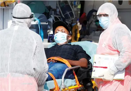  ?? Reuters ?? A medical staff member looks on while a patient is carried on a stretcher as he arrives at a hospital on Monday, as the spread of COVID-19 continues in Rome.