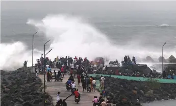  ?? AFP ?? People walk along the breakwater at Kasimedu fishing harbour in Chennai. Both Andra Pradesh and Tamil Nadu are bracing for cyclone Phethai, which is expected to hit today.