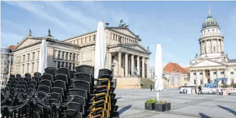  ?? FOTO: JENS KALAENE/DPA ?? Gespenstis­che Ruhe am Berliner Gendarmenm­arkt: Gestapelte Stühle eines Cafés vor dem Schauspiel­haus (links) und dem Französisc­hen Dom.