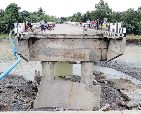  ??  ?? People explore a bridge damaged by flooding brought about by Tropical Storm Tembin in Zamboanga del Sur in the southern Philippine­s.