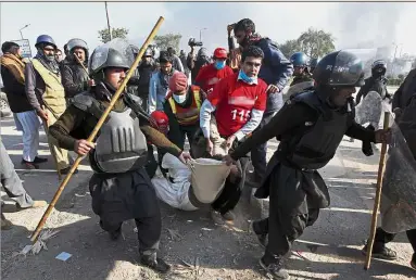  ??  ?? Tense situation: Pakistani police officers carrying an injured protester during the clash in Islamabad, Pakistan. — AP