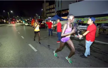  ??  ?? Internatio­nal runners grab a bottle of water to hydrate themselves during the run.