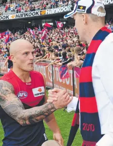  ??  ?? CHAMPIONS: Nathan Jones greets Demon great Jim Stynes in 2010, and leads the team out in Round 1 this season, top.