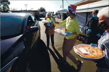  ?? PHOTOS BY SHMUEL THALER — SANTA CRUZ SENTINEL ?? Volunteer Kathryn Nance brings a traditiona­l turkey dinner to a waiting motorist during Grey Bears’ drive-thru holiday meal distributi­on on Sunday.