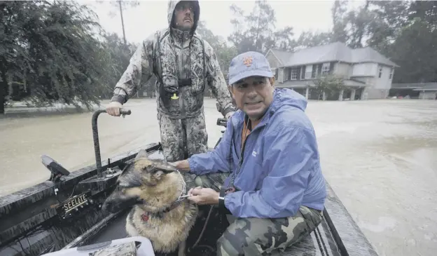  ?? PICTURE: DAVID J PHILLIP/ AP ?? 0 Joe Garcia, right, and his dog Heidi ride in Murphy fire department’s Todd Herrington’s boat after being rescued from his flooded home