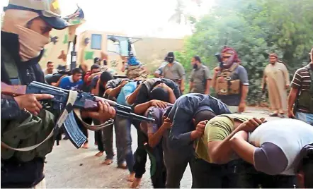  ??  ?? Chilling scenario: IS militants leading away captured Iraqi soldiers dressed in plain clothes after taking over a base in Tikrit in June last year. It is believed that the bodies in the graves could be of these soldiers. — AP