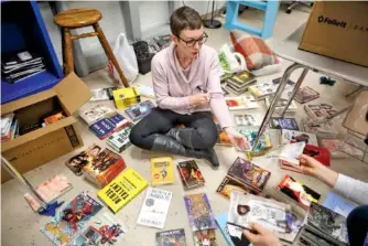  ?? STAFF PHOTO BY DOUG STRICKLAND ?? English teacher Katelyn Dix sorts through donated books in her classroom at The Howard School on Saturday.