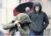  ??  ?? WINDSWEPT People in Glasgow battle the storm