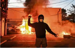  ?? — AFP ?? Streets on fire: A protester posing in front of a burning car during the riots in Minneapoli­s on May 29.