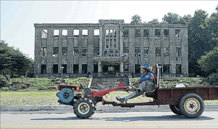  ?? YONHAP / EFE ?? Un granjero surcoreano en Choerwon, pueblo próximo a la frontera con Corea del Norte pasa delante del antiguo edificio del norcoreano Partido de los Trabajador­es