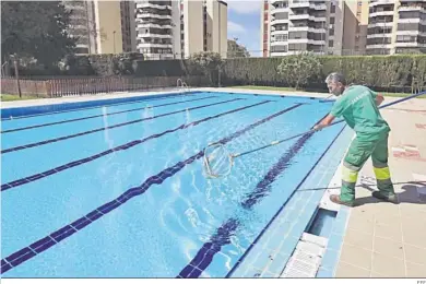  ?? EFE ?? Un hombre limpia una piscina en una comunidad de vecinos de Torremolin­os.