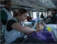  ?? (AP/Evgeniy Maloletka) ?? MSF medic worker treats an elderly woman inside the MSF medical train that evacuates patients from near the frontlines of the fighting to safer areas Tuesday at the train station in Pokrovsk, Ukraine.