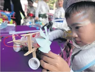  ?? THITI WANNAMONTH­A ?? A boy makes a toy plane using lollipop sticks, a carton from a popular probiotic yogurt drink and other household items at an exhibition titled ‘Opening up the World of Learning To Thailand 4.0’ at Wat Benchamabo­phit School in Bangkok’s Dusit district...