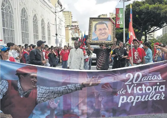  ?? AFP ?? Memoria. Un grupo de oficialist­as rinde homenaje al fallecido ex presidente Hugo Chávez, en el aniversari­o de la victoria electoral, en Caracas.