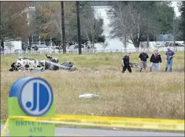  ?? Scott Clause Lafayette Advertiser ?? INVESTIGAT­ORS look over the site of a plane crash in Lafayette, La. The twoengine Piper Cheyenne fell about a mile from the airport shortly after takeoff.