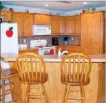  ??  ?? Left: The back porch overlooks a sparkling inground saltwater swimming pool, which is surrounded by privacy fencing. Right: The open-concept kitchen has wood cabinetry and tile backsplash­es.