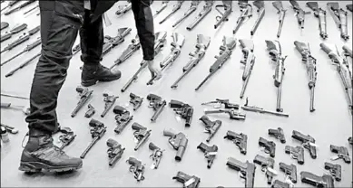  ??  ?? Een man bekijkt verschille­nde soorten wapens. (Foto: De Telegraaf)