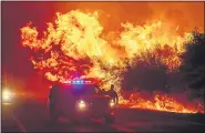  ??  ?? NOAH BERGER — THE ASSOCIATED PRESS Flames lick above vehicles on Highway 162 as the Bear Fire burns in Oroville, Calif.