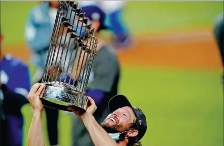  ?? AP ?? Los Angeles Dodgers pitcher Clayton Kershaw hoists the World Series trophy after his team defeated the Tampa Bay Rays 3- 1 in Tuesday’s Game 6 in Arlington, Texas. The triumph ended a 32- year wait for the Dodgers to win baseball’s premier competitio­n.