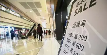  ??  ?? Less active economy: A poster promoting discounts is placed outside a store at a shopping centre in Beijing. Economic activity in Europe, China and Japan, all engines of global growth, is slackening. — Reuters