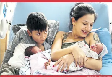  ?? STEVE RUSSELL TORONTO STAR ?? Melissa Arrubla says hello to new daughter Elena, as her son Anderson, 7, helps to hold his brother Elian. The twins, both weighing over 6 pounds, decided to show up a few hours before they were scheduled be induced.