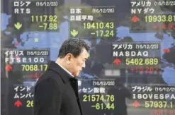  ??  ?? TOKYO: A man walks by an electronic stock board of a securities firm in Tokyo yesterday. Stock markets in Japan and China declined yesterday in light trading after Christmas with most other Asian markets closed. — AP