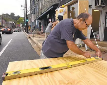  ?? AMY DAVIS/BALTIMORE SUN ?? Brian Healy cuts plywood as other volunteers help businesses on Main Street in Ellicott City prepare for anticipate­d flooding from Hurricane Florence. The storm appears headed for the Carolinas; its local impact will depend on how the hurricane tracks.