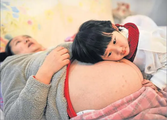  ?? CHINA DAILY / REUTERS ?? La hija de Li Yan acaricia el vientre de su madre, embarazada de su segundo hijo, en la ciudad china de Hefei