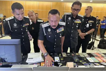  ?? — Bernama photo ?? Ruslin (second left) takes a closer look at some of the items seized during the operation.