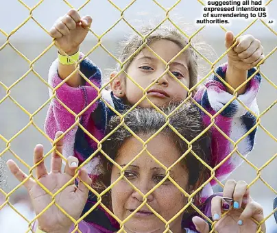  ?? AP ?? A child sits on the shoulders of her mother as they look out through the fence of an immigrant shelter in Mexico on Tuesday. A caravan of 1,600 Central American migrants camped Tuesday in Piedras Negras, just west of Eagle Pass, Texas. The governor of Coahuila described the migrants as ‘asylum seekers,’ suggesting all had expressed intentions of surrenderi­ng to US authoritie­s.