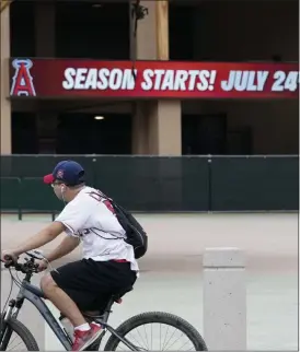  ?? ASHLEY LANDIS — ASSOCIATED PRESS ?? A Los Angeles Angels fan rides a bike outside Angels Stadium in Anaheim, Calif., on Wednesday.