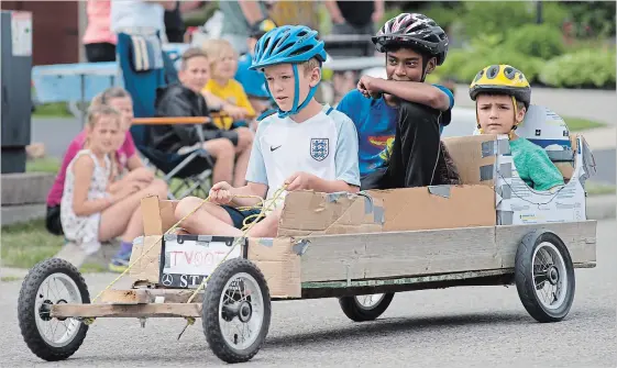  ?? PETER LEE WATERLOO REGION RECORD ?? From left, Tyler MacTavish, 10, Vithushan Kumanan, 12, and Owen MacTavish, 7, pilot their car down the street as spectators look on.