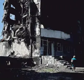  ?? NATACHA PISARENKO/AP ?? A woman walks past a building destroyed Tuesday in Russian shelling in Borodyanka, on the outskirts of Kyiv, Ukraine.