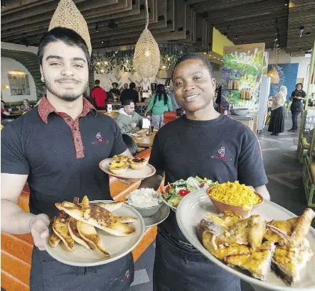  ?? IAN KUCERAK ?? Servers Karan Goswami, left, and Descent Zikhali show off some of the dishes on the extensive menu at Nando’s restaurant Wednesday at the 4228 Gateway Blvd. location in Edmonton.