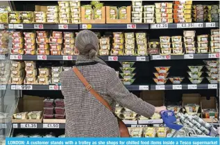  ?? ?? LONDON: A customer stands with a trolley as she shops for chilled food items inside a Tesco supermarke­t store in east London. – AFP