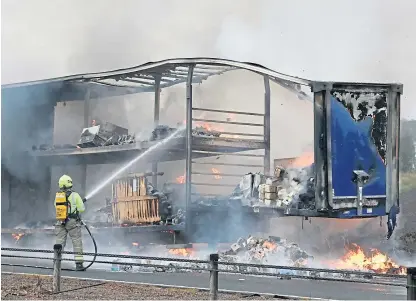  ?? Picture: Gareth Jennings. ?? A firefighte­r tackles the lorry blaze and, below, impatient motorists were caught on camera driving the wrong way.