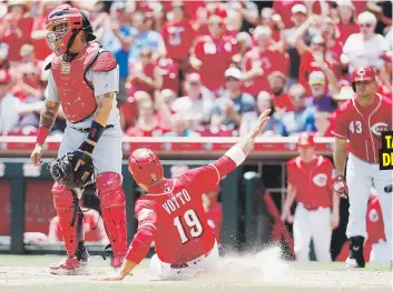  ??  ?? El receptor de los Cardenales, el boricua Yadier Molina, no puede hacer nada para evitar la anotación de Joey Votto en la victoria de los Rojos. TARDÍO DISPARO