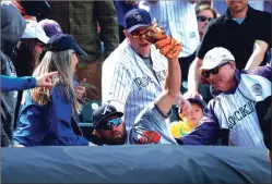  ?? DAVID ZALUBOWSKI / The Associated Press ?? Atlanta’s Charlie Culberson (center) holds up his glove to show the out after making a diving catch into the stands on Sunday at Colorado.