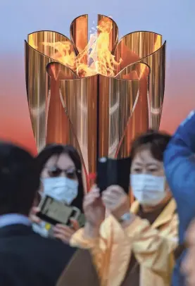  ??  ?? Visitors arriving from Greece gather for photos Saturday in front of the Tokyo 2020 Olympic flame outside Sendai Station. PHILIP FONG/AFP VIA GETTY IMAGES