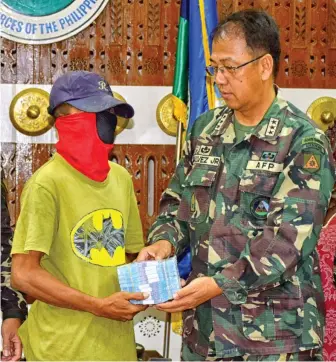 ??  ?? A photo released by the military’s Western Mindanao Command shows Lieutenant General Carlito Galvez, Jr., handing over some P1 million in reward money to a masked man in Zamboanga City. The man allegedly tipped off the military on the presence of Abu...