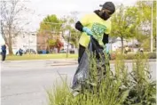  ??  ?? Kenneth Griffin, 29, who grew up and still lives in Englewood, joins dozens of volunteers cleaning empty lots along Halsted Street on Saturday. He is now a Chicago police officer.