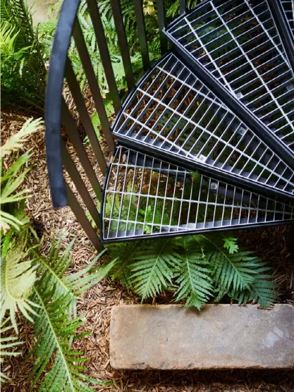  ??  ?? ABOVE An external steel spiral staircase by All Metal Design connects a generous covered balcony to the garden. Lucky lady ferns fan out beneath. OPPOSITE Bendigo Pebbles aggregate from Eco Outdoor contrasts with sandstone pavers recycled from the former garden and the chunky bench base in sandstone from Gosford Quarries. The tall planter from Garden Life is painted Resene Chicago, while the smaller planter has belonged to the client for some time. Hardy dwarf mondo grass provides the ground cover.