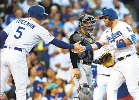  ?? Photograph­s by Alex Gallardo Associated Press ?? JUSTIN TURNER slaps hands with teammate Freddie Freeman after Turner’s three-run home run into the left-field pavilion in the third inning gave the Dodgers a 7-0 lead and completed their scoring. The Dodgers look to complete a sweep of Miami on Sunday.