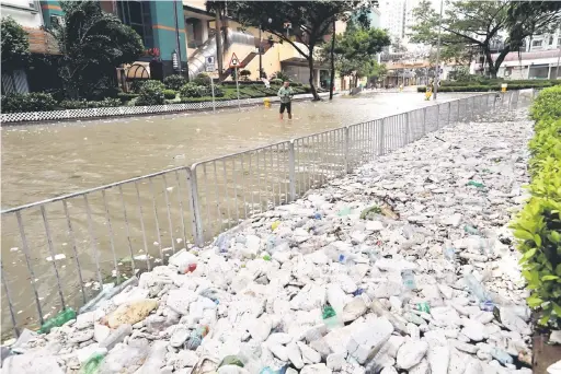  ?? — Gambar Reuters ?? TERJEJAS: Sampah-sarap dan busa pembungkus­an memenuhi kaki lima jalan setelah Hong Kong dilanda banjir kilat susulan kemaraan Hato, semalam.