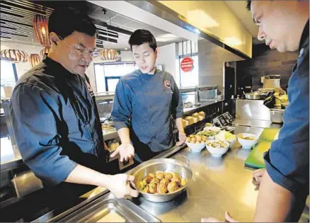  ?? Photog raphs by Don Bartletti Los Angeles Times ?? PANDA EXPRESS Executive Chef Andy Kao, left, the inventor of orange chicken, tries meatball recipes with product manager Adrian Lok and Jimmy Wang, director of culinary innovation, at the company’s Innovation Kitchen in Pasadena.