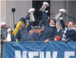  ?? BARRY CHIN/THE BOSTON GLOBE VIA AP ?? New England quarterbac­k Tom Brady, center, coach Bill Belichick, right, and free safety Devin McCourty greet the crowd during Tuesday’s parade in Boston.